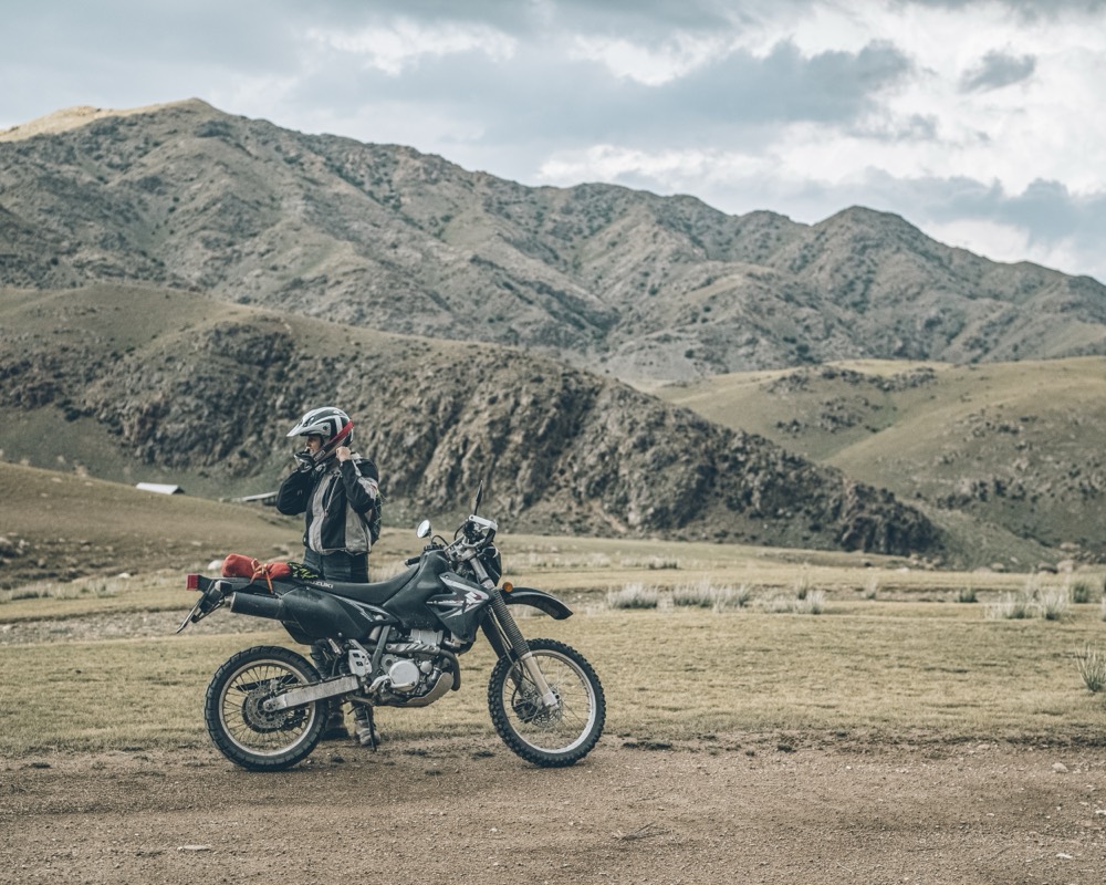 Motorcyclist crossing a broad valley in Kyrgyzstan